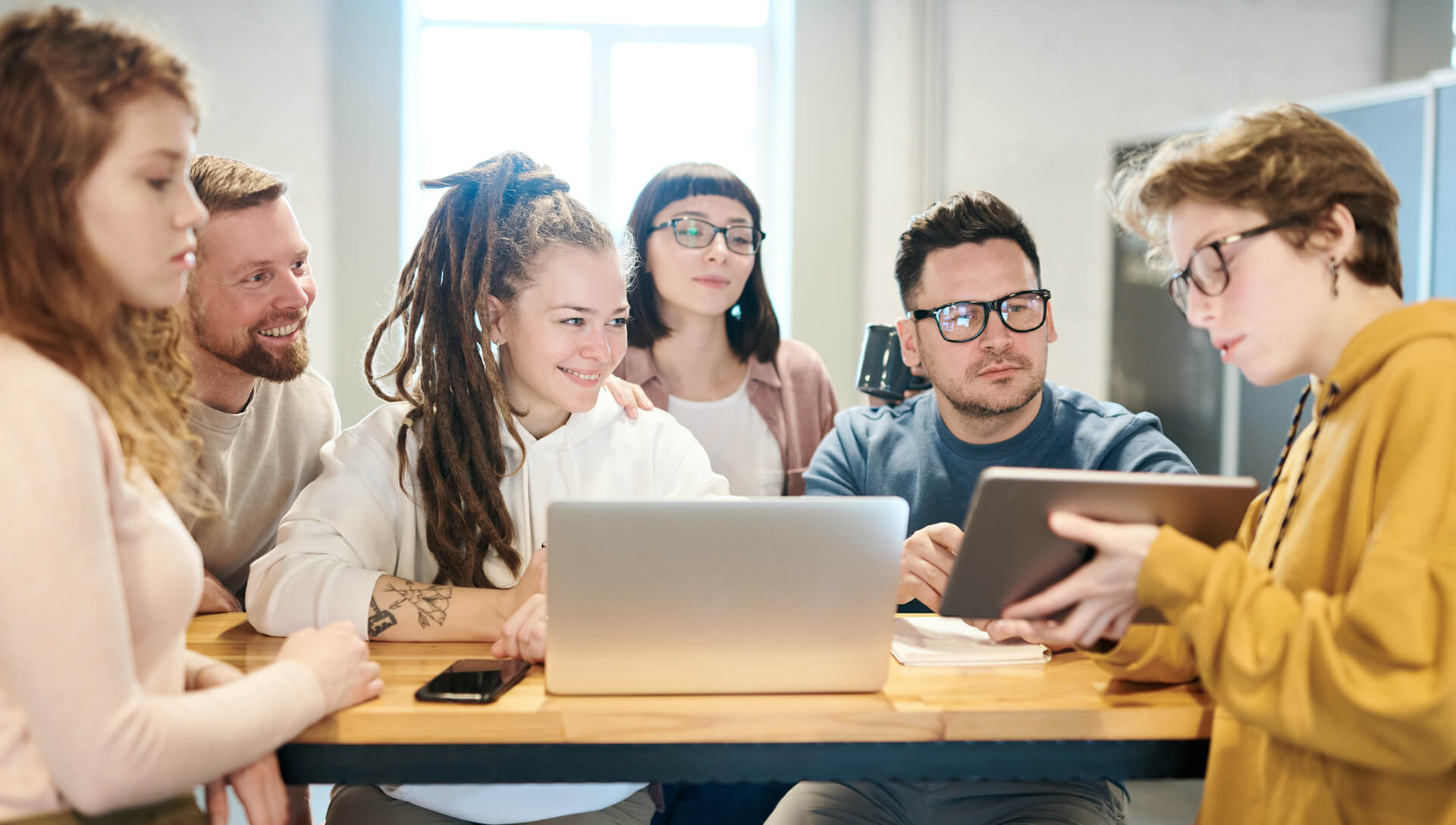 Colleagues gathered around laptops at a shared office table