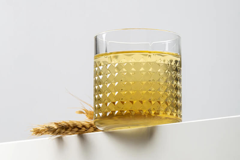 Patterned drinking glass next to ears of wheat